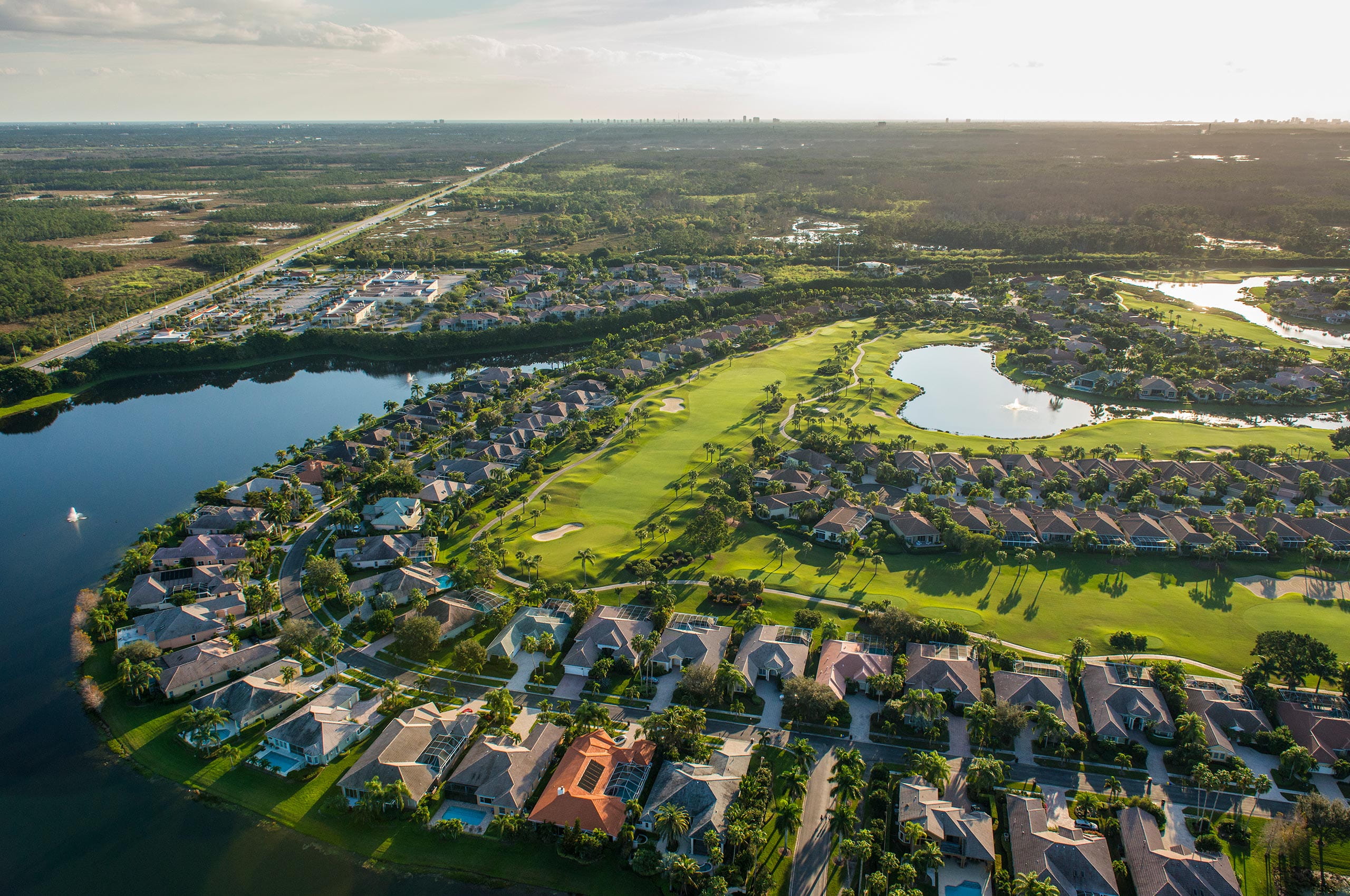  Vista aérea del campo de golf con casas, árboles y caminos en una zona residencial.