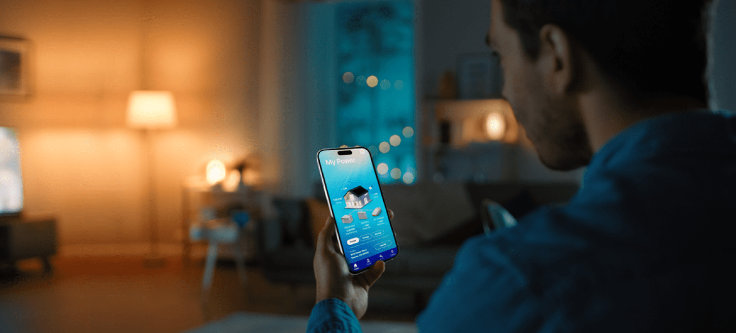 A man holding a smartphone in front of a television.
